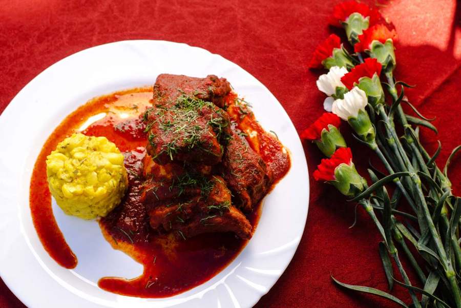 Carne en salsa roja con mote de maíz y claveles